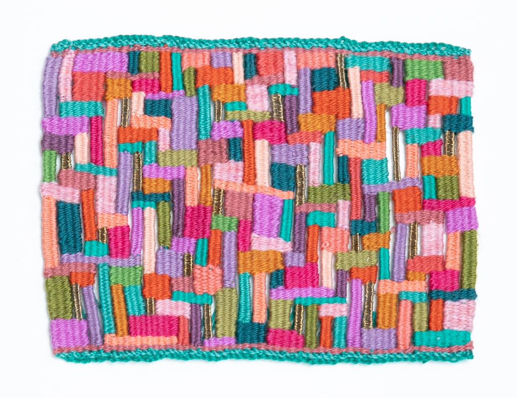 a tapestry that looks like a whole bunch of small blue, purple, pink, orange, and green rectangles woven together to make a rectangle